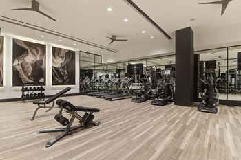 A gym with a variety of equipment and a large mirror on the wall.